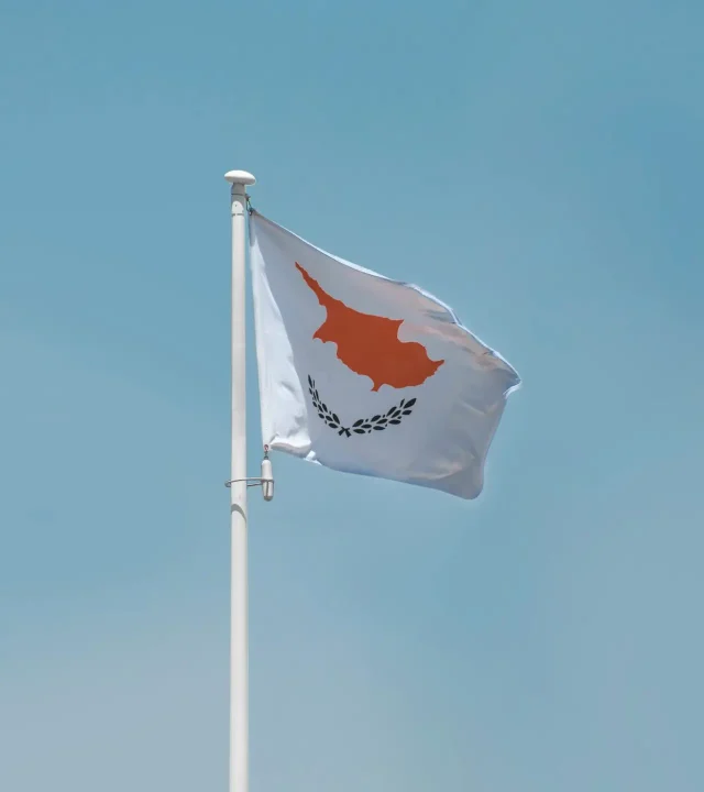 The Cyprus national flag waving on a flagpole against a clear blue sky, showcasing patriotism.