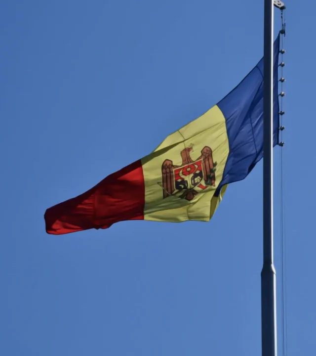 The Moldovan flag elegantly flutters on a flagpole under a clear blue sky.